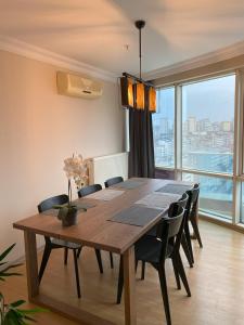 un tavolo da pranzo con sedie e una grande finestra di Super Large, Lux, Romantic and Modern Duplex Penthouse, 5 min to Forum Istanbul, Bus, Metro, Tram, Major Shopping Centers, & Many More Rent follows governmental instructions a Istanbul