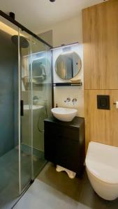y baño con lavabo y ducha acristalada. en ApartamentLesznoPL Family Friendly, en Leszno