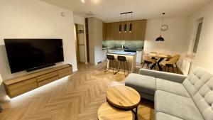 een woonkamer met een bank en een flatscreen-tv bij ApartamentLesznoPL Family Friendly in Leszno