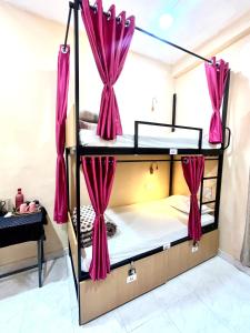 a bedroom with two bunk beds with pink curtains at The BackpackStack in Ujjain