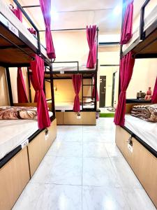 a room with four bunk beds with pink curtains at The BackpackStack in Ujjain