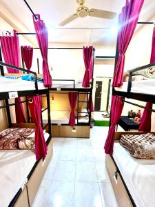 a room with three bunk beds with pink curtains at The BackpackStack in Ujjain