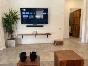 sala de estar con TV de pantalla plana en la pared en PATAMAAN COTTAGES, en Nathon Bay