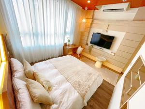 una camera da letto con un letto bianco e una televisione di 台南悠然民宿unabnb a Tainan