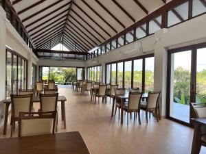 a dining room with tables and chairs and windows at Sumator Resort Chiangrai สูมาเต๊อะ รีสอร์ท เชียงราย in Ban Huai Phaya Kao