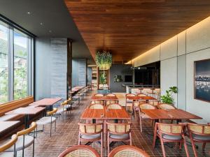 a restaurant with wooden tables and chairs and windows at The Royal Park Canvas Fukuoka Nakasu in Fukuoka