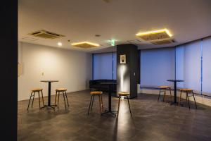 a room with stools and tables in a room with a piano at 米子シティガーデンズホテル Yonago Citygardens Hotel in Yonago