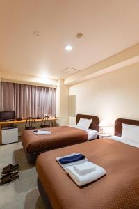 a hotel room with two beds and a television at 米子シティガーデンズホテル Yonago Citygardens Hotel in Yonago