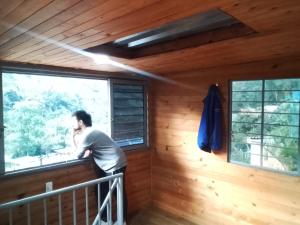 a man looking out of a window in a cabin at HyH Estadía Gourmet in Ibagué