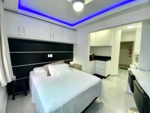 a bedroom with a large white bed and a kitchen at Kitnet em Prédio com Vista Mar in Balneário Camboriú