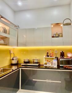 eine Küche mit weißen Schränken und einer gelben Wand in der Unterkunft Êm Home 3 Phòng Ngủ in Hue