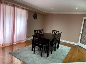a dining room table with chairs and a clock on the wall at Room for Rent Room 1 in Brampton
