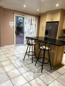 a kitchen with a black counter and two bar stools at Room for Rent Room 1 in Brampton