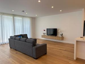 a living room with a couch and a flat screen tv at New 2-story house with 4 bedrooms and 3 shower rooms in Burwood