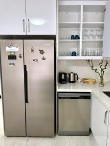 una cocina con nevera de acero inoxidable y armarios blancos en NEW Citrus Garden Home Duplex, en Mudanya