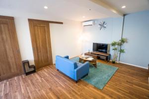 ein Wohnzimmer mit einem blauen Sofa und einem TV in der Unterkunft OASIS NANIWA in Osaka