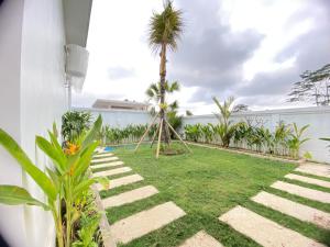 un patio trasero con palmeras y césped en Namika Ubud en Tegalalang