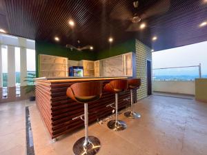 a bar with two stools in a room with windows at Ganges Blossam, Haridwar-Rishikesh Road - A Four Star Luxury Hotel in Rishīkesh