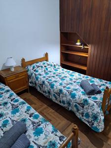 a bedroom with two beds and a dresser and a night stand at Hostel Belgrano Home in Monte Grande