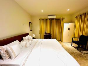 a bedroom with a large white bed with yellow curtains at Ceylon Kingsmen Garden Hotel - Katunayake in Negombo