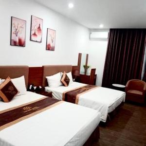 una habitación de hotel con 2 camas y una silla en LuxTel Hotel Tây Hồ, en Hanói