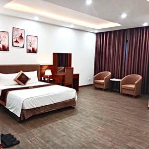 Habitación de hotel con cama, escritorio y sillas en LuxTel Hotel Tây Hồ, en Hanói