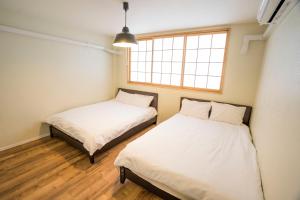 2 Betten in einem Zimmer mit Fenster in der Unterkunft OASIS NANIWA in Osaka