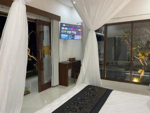 Cette chambre comprend un lit avec des rideaux et une télévision. dans l'établissement Namika Ubud, à Tegalalang
