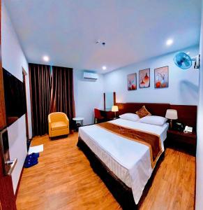 ハノイにあるLuxTel Hotel Tây Hồのベッドと椅子付きのホテルルーム