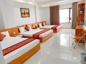 a hotel room with two beds and a desk at Sail Hotel Hạ Long in Ha Long