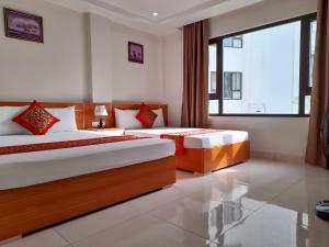 a bedroom with two beds and a large window at Sail Hotel Hạ Long in Ha Long