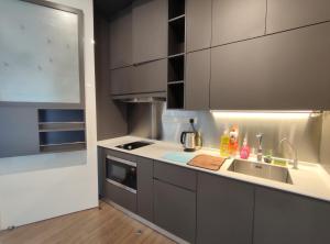 uma cozinha com armários cinzentos e um lavatório em Ceylonz Suite, Bukit Bintang em Kuala Lumpur
