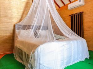 a bedroom with a bed with a mosquito net at BLACK SWEET BUNGALOW in Gili Air
