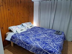 um quarto com uma cama com um edredão azul e branco em Hostel Belgrano Home em Monte Grande