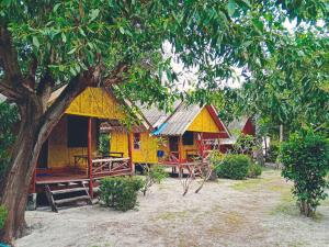 ein gelbes Haus mit einem Picknicktisch und einem Baum in der Unterkunft Andaman Bay Bungalow in Ko Lanta