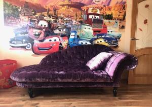 ウージュホロドにあるSemeyny Guest Houseの壁の前に紫色のソファーがあり、映画の壁画が飾られています。