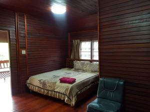 a bedroom with a bed and a green chair at RuysukJo Resort&Pool in Udon Thani