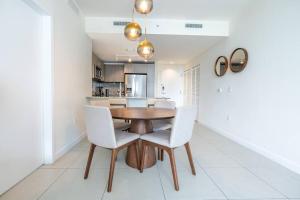 una sala da pranzo con tavolo in legno e sedie bianche di Stunning Apartment in Downtown Doral a Miami