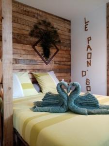 Dos cisnes de toalla haciendo un corazón en una cama en Le paon de bois, en Saint-Mards-en-Othe