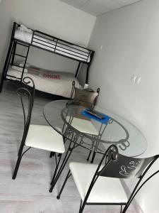 a glass table and chairs in a room with a bed at Studio 1 pièce in Bussang