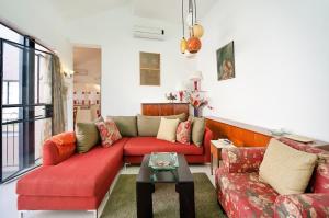 ein Wohnzimmer mit einem roten Sofa und einem Tisch in der Unterkunft Lovely 2BR Apt w Balcony in Neve Tzedek Area Sea N' Rent in Tel Aviv