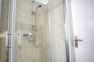 a shower with a glass door with a shower head at Homefy Sleep & Relax Apartment mit frei parken, in Toplage in Essen