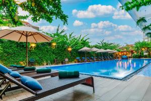a pool at a resort with chairs and umbrellas at Wyndham Garden Hoi An Cua Dai Beach in Hoi An