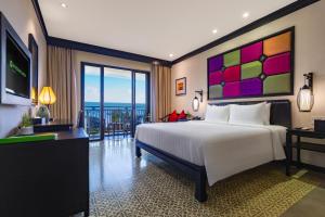 a bedroom with a large white bed and a television at Wyndham Garden Hoi An Cua Dai Beach in Hoi An