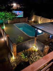 una piscina por la noche con TV en el fondo en Pousada Morrison, en Praia do Rosa