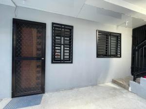 a white wall with two windows and a door at Canlubang Luxury Apartment in Canlubang