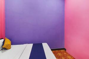 a bedroom with a purple wall and a bed at OYO 78880 Rajdhani Hotel in Kākori