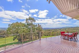 a wooden deck with red chairs and a table on it at McLaren Eye in Kangarilla