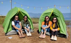 um grupo de pessoas sentadas em frente às tendas em Malshej Ghat Hill Top Camping em Otūr