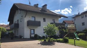 ein weißes Haus mit einem Spielplatz davor in der Unterkunft Apartment Obermair in Bruneck